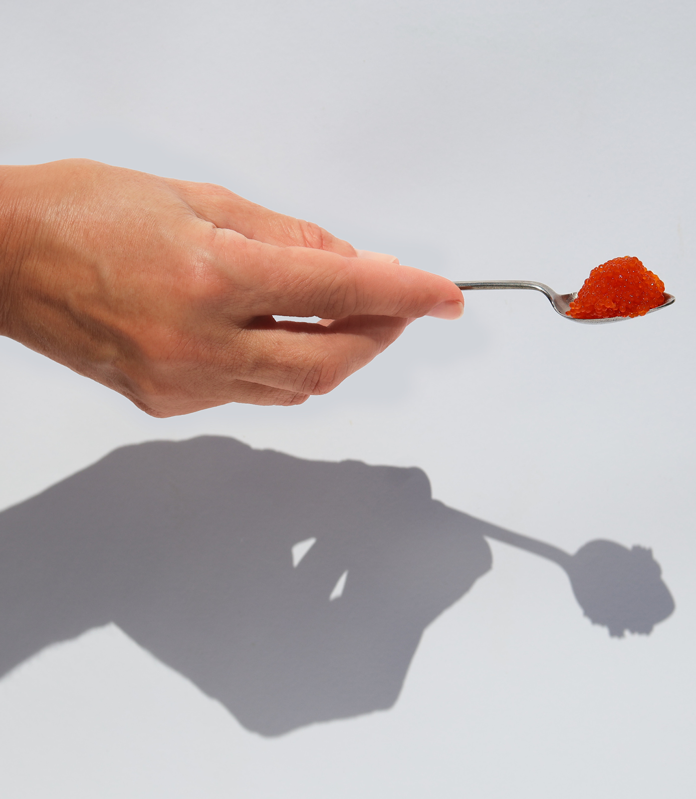 Young woman's hand holding spoonful of Viking Imports Red Pearl Seaweed Caviar