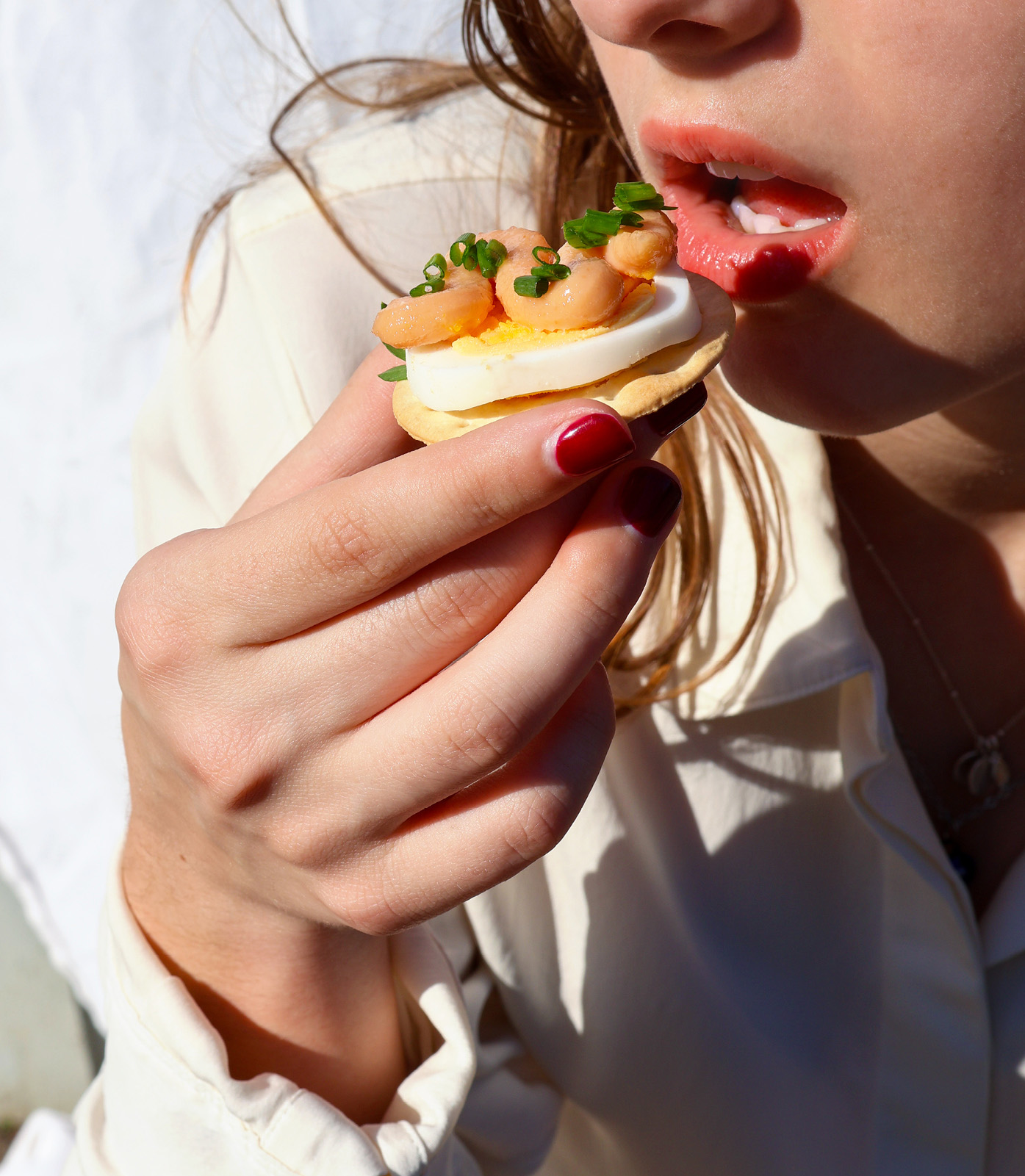 Young woman about to eat cracker topped with Viking Imports Cod Roe Creme