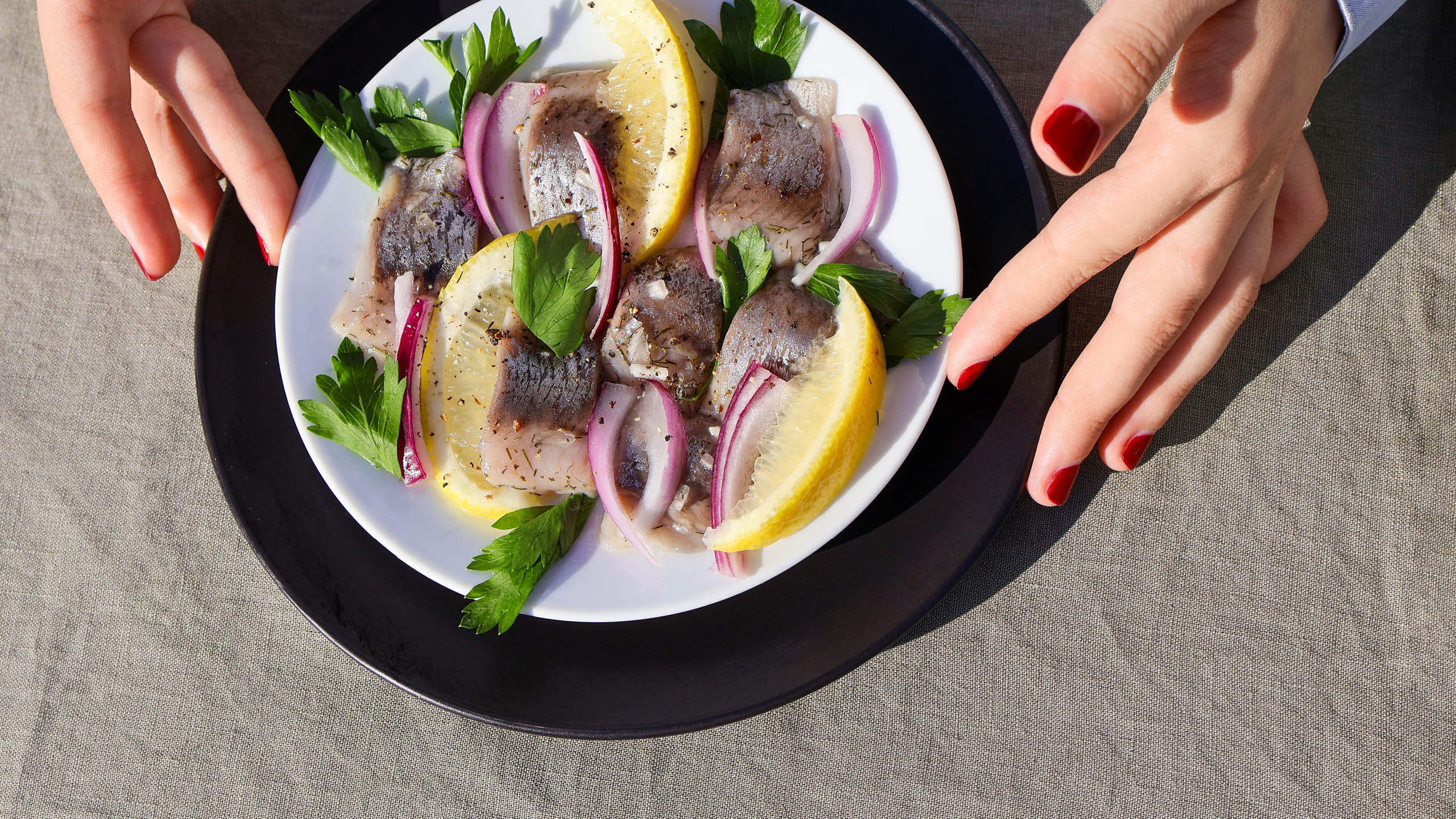 Young woman's hands with platter of Viking Imports Pickled Herrings