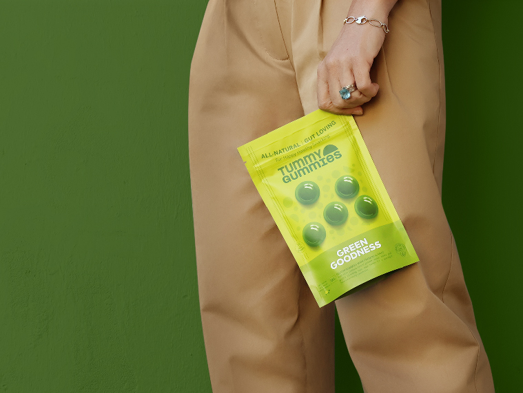 Woman holding packaging for Tummy Gummies Green Goodness